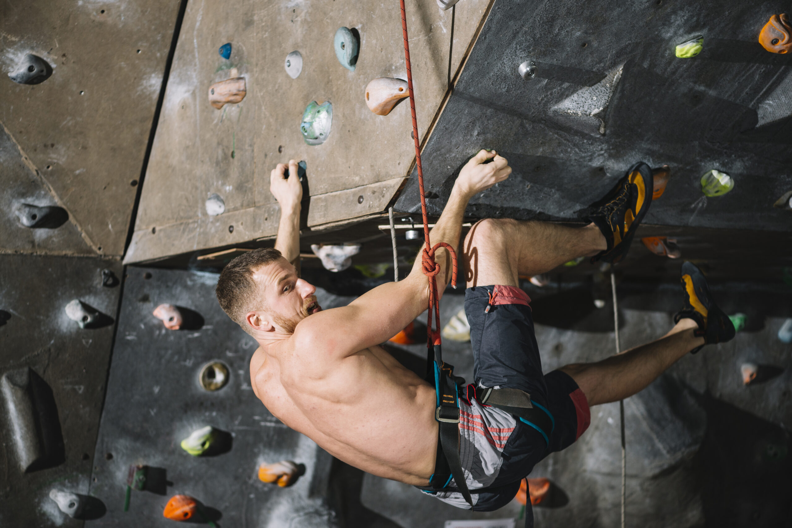 A climber practices rappelling on a low-risk surface, such as a boulder, while using proper safety equipment and techniques.