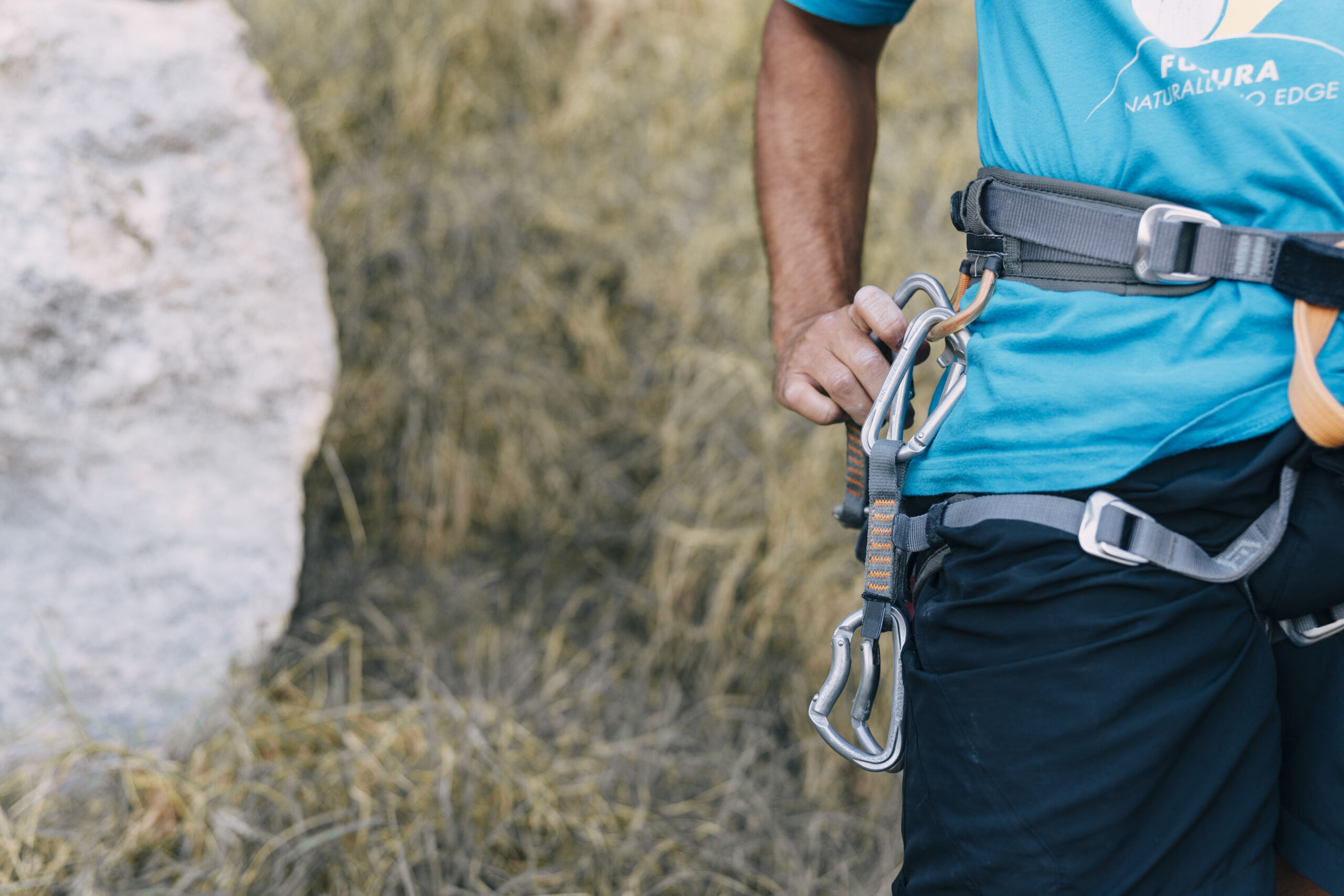A close-up photo of a climber tying a rappel anchor using a sling and carabiner, showcasing the proper technique for creating a secure anchor point.