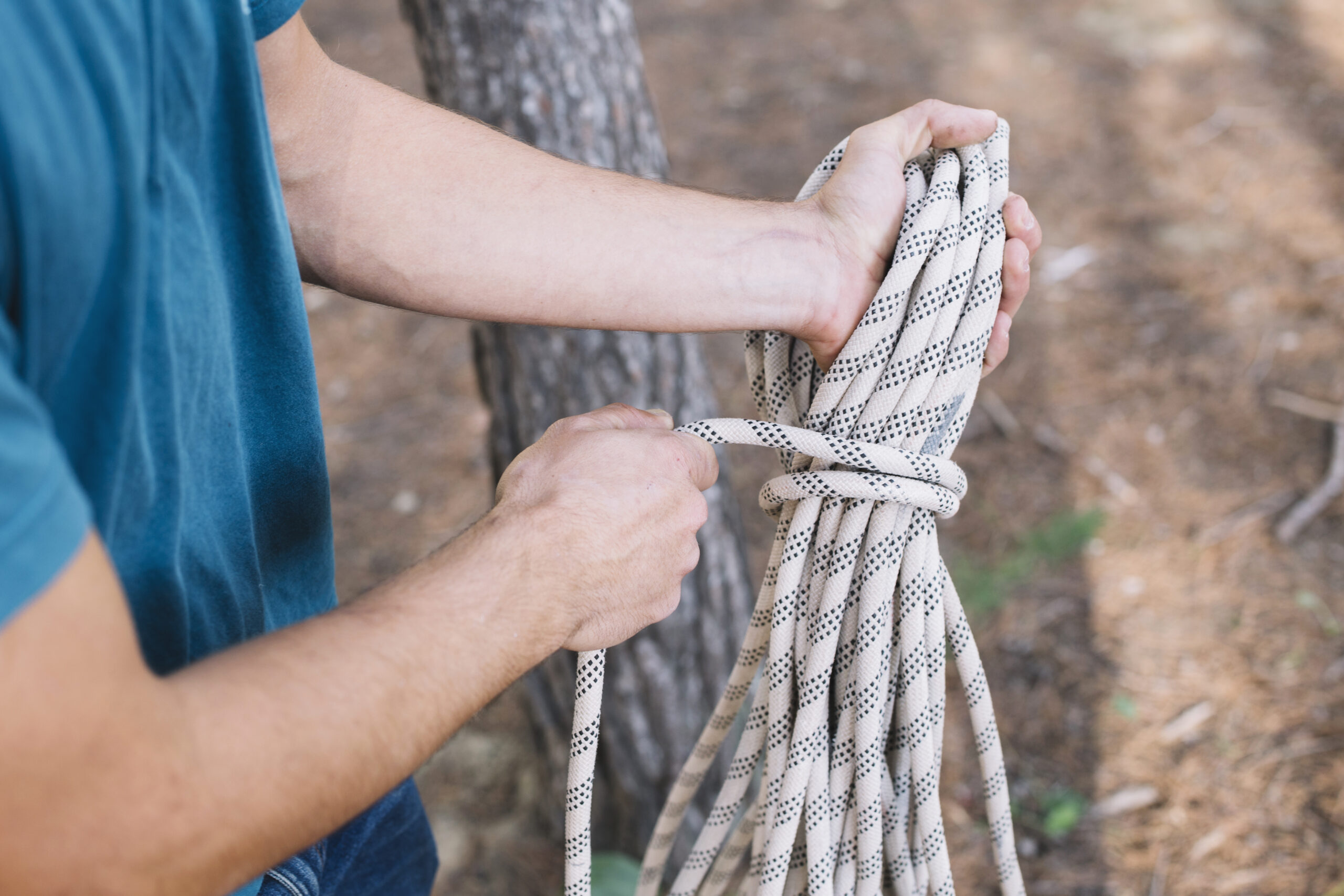 A person holding up different types of ropes and examining their texture and thickness to determine which one is best suited for rappelling.