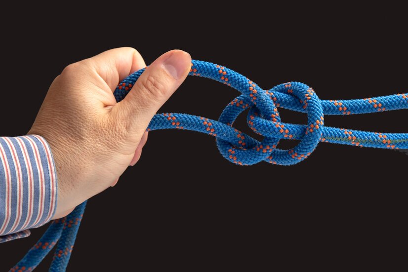 A close-up of a person's hand positioning while using the Munter hitch technique, which involves tying a knot in the rope to create a friction brake and controlling your descent with your hands.