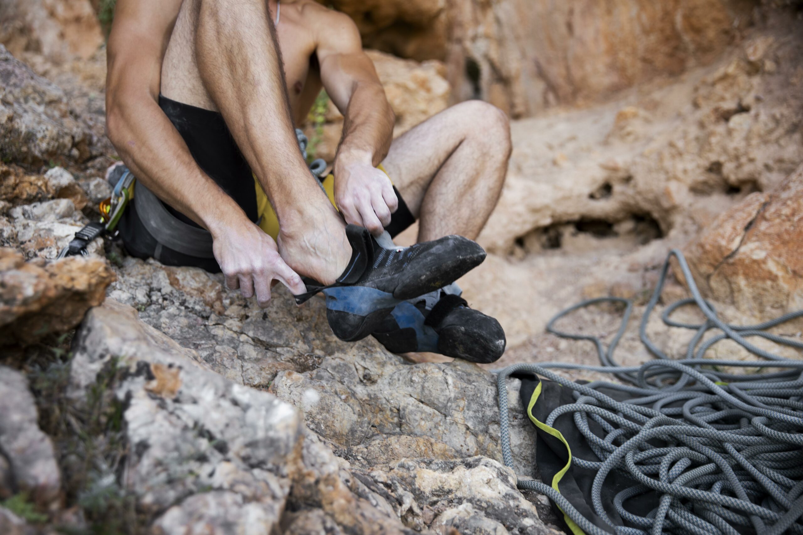 A close-up of a person's hands tying a secure knot on a rope as they prepare to start their rappelling descent.